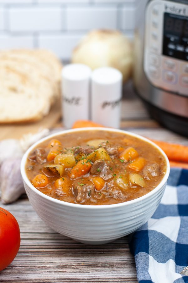 white bowl of beef stew in front of the instant pot